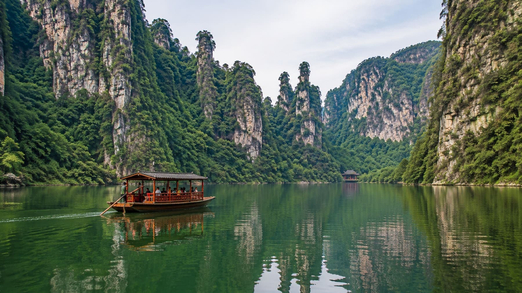 Wooden boat on Baofeng Lake between green cliffs near Zhangjiajie